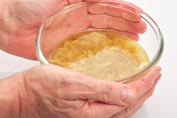 Chef's hands hugging a glass bowl of chicken broth