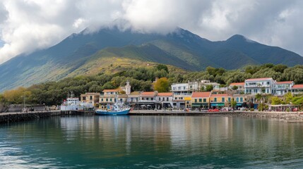 Fototapeta premium Scenic view of a coastal village with colorful buildings and a fishing boat near a mountain backdrop