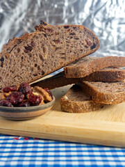 Pan de masa madre perfectamente horneado con nueces y arándanos, presentado sobre una tabla de madera / Perfectly baked sourdough bread with walnuts and cranberries, presented on a wooden board