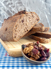 Pan de masa madre perfectamente horneado con nueces y arándanos, presentado sobre una tabla de madera / Perfectly baked sourdough bread with walnuts and cranberries, presented on a wooden board