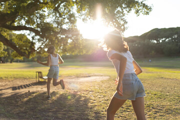Two children joyfully running in a sunlit park