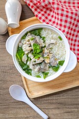 Rice soup with fish in white bowl on wooden background