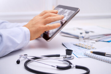 Medical professional examines diagnostic images on a tablet while surrounded by equipment in a...