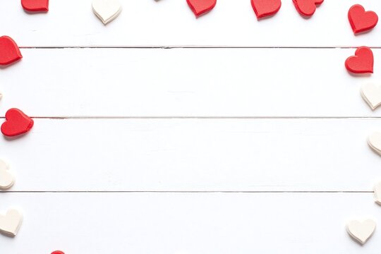 Rustic white wooden surface scattered red and white heart shaped objects