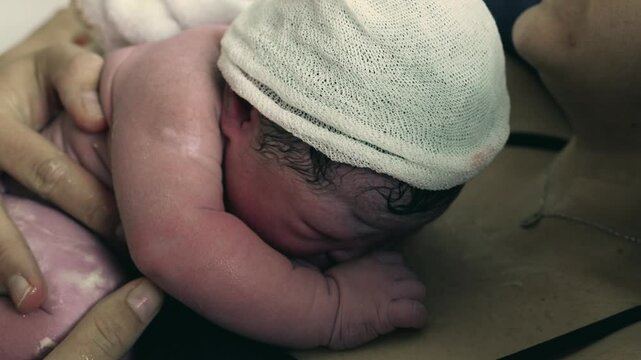 Real life birth moment of newborn baby right seconds after being born, welcoming a new human being into this world