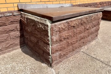 Basement entrance in the building of house has window is located below ground level. Window is covered with galvanized steel in brown color sheet to protect basement from precipitation during rain