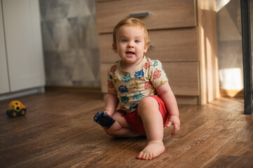 Naklejka premium Cute little boy playing with colorful toys on floor at home.