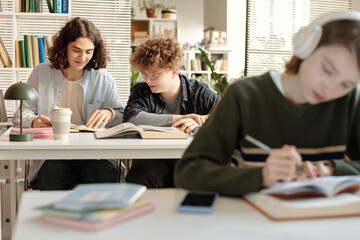 Over shoulder shot of two boy students working together sitting at table in college classroom while preparing for exams copy space 