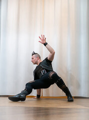 A man in rock clothes performs dance moves. A metal man with a mohawk on his head. Man in motion...