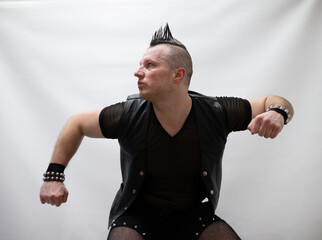 A man in rock clothes performs dance moves. A metal man with a mohawk on his head. Man in motion...