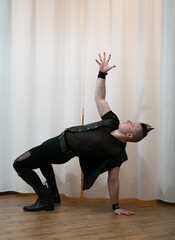 A man in rock clothes performs dance moves. A metal man with a mohawk on his head. Man in motion...