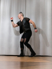 A man in rock clothes performs dance moves. A metal man with a mohawk on his head. Man in motion...