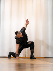 A man in rock clothes performs dance moves. A metal man with a mohawk on his head. Man in motion...