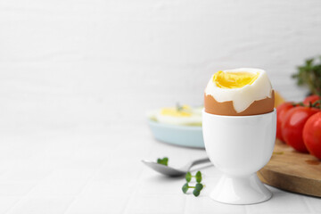 Soft boiled egg on white tiled table, closeup. Space for text