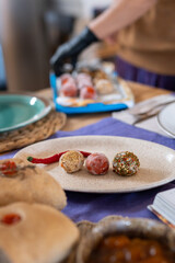 A variety of homemade soft goat cheese balls coated in spices and herbs, showcasing cheesemaking craftsmanship and eco-friendly, healthy food. Table setting with spicy cheese balls on the plate