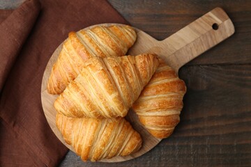 Tasty fresh croissants on wooden table, top view. Puff pastry