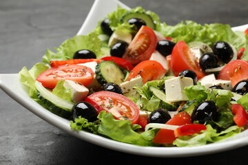 Delicious fresh Greek salad on black table, closeup
