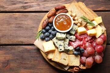 Different types of delicious cheese and other snacks on wooden table, top view. Space for text