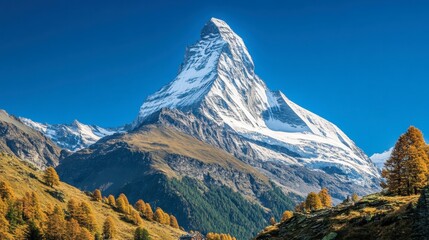 Fototapeta premium A breathtaking view of the Matterhorn mountain towering above the Swiss Alps, snow-covered peaks against a clear blue sky.