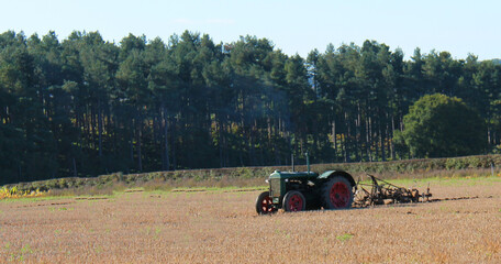 Fototapeta premium A Classic Vintage Tractor and Plough in a Farming Field.