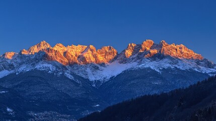 Fototapeta premium The Italian Alps at dawn, with the first rays of light casting a warm glow over the snow-covered mountain tops.