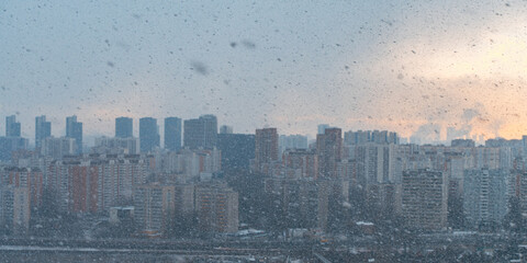 Panorama of a big city, it is snowing, cloudy and clear sky with snowflakes, aerial view of residential high-rise buildings.