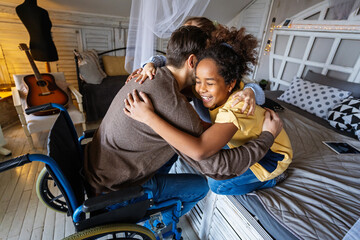 Multiethnic, diverse daughters and single father in a wheelchair sharing a warm moment at home