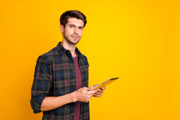 Photo of nice guy with e-reader in hands making corporate notes think over startup idea wear casual checkered shirt isolated yellow color background