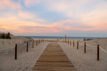 Wooden boardwalk leading to sandy beach at sunset