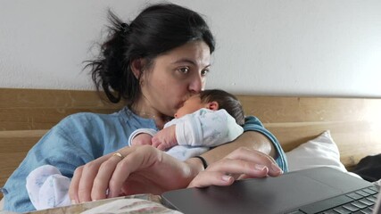 Mother is focused on her laptop while her newborn baby sleeps in her arms. challenge of juggling work and childcare, with the mother deeply engrossed in her tasks