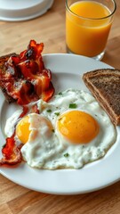 Fototapeta premium Delicious breakfast featuring fried eggs, bacon, toast, and fresh orange juice on a wooden table