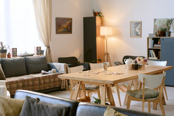 Wide shot of fully equipped living room with comfortable furniture, wooden table with bingo game on...