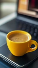 Golden Hour Coffee Break: A Yellow Cup of Espresso on a Laptop