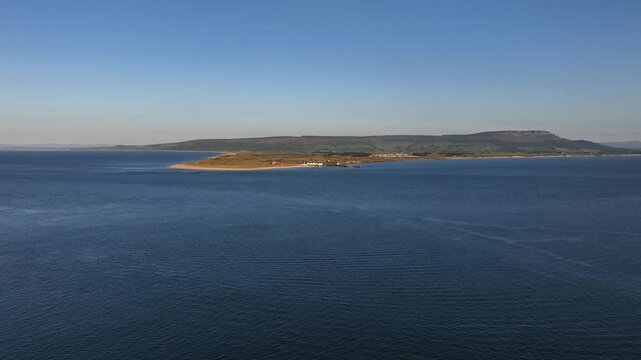 Magilligan Point, Lough Foyle Ferry, County Derry, Northern Ireland, June 2023. Drone ascends above calm open water facing east as seen from Greencastle Harbour in Ireland.