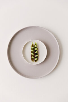 Marrow fat peas still in their skin lying on a small plate.