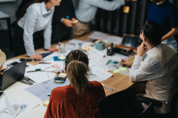 A multiracial group of business colleagues engaged in late evening brainstorming, analyzing...