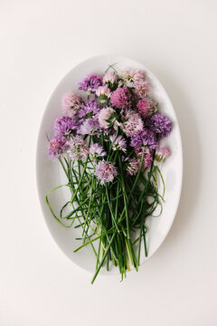 A bunch of flowering chives gathered on a oval shaped dish.
