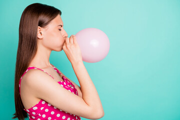 Profile side photo of upset lady trying to inflating balon wearing polka dot dress isolated over teal turquoise background © deagreez