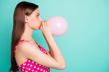 Profile side photo of astonished girl inflating balon looking wondering wearing polka dot dress singlet isolated over teal turquoise background