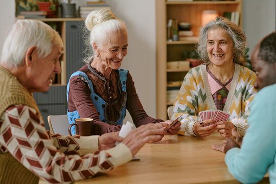 Senior people smiling and enjoying playing cards together in nursing home