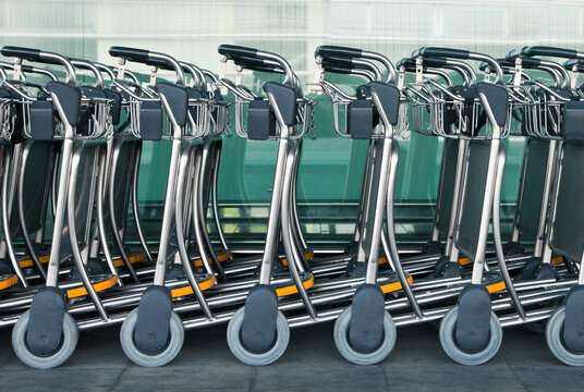 A row of empty luggage carts at an airport.