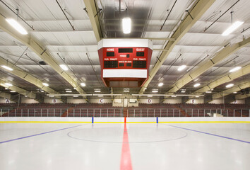 An indoor ice hockey arena, with an overhead electronic score board.