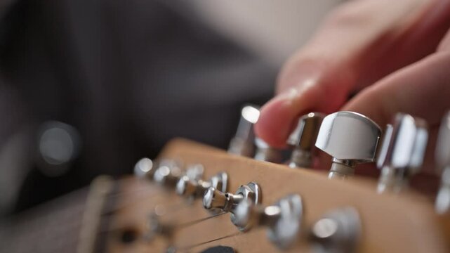 Tuning a new electric guitar. The musician uses a peg on the fretboard to tighten the string to get the right sound.
