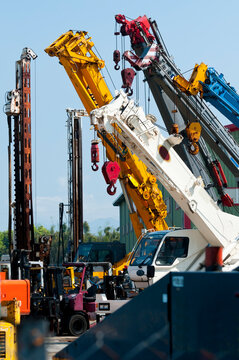 A group of mobile cranes with hooks and pulleys, dockyard lifting equipment.