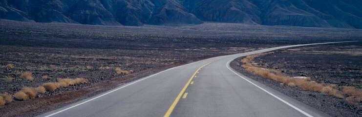 A highway curving through desolate area of Death Valley National Park, California, USA.