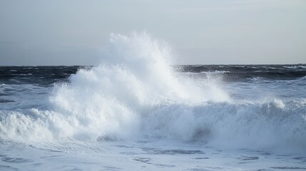 Powerful ocean waves crashing and spraying against a cloudy sky during a storm