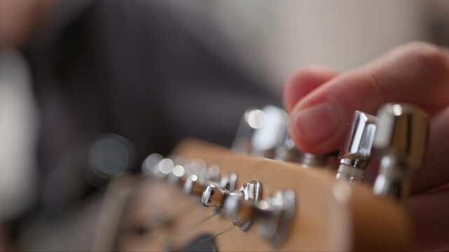 Tuning an electric guitar. The musician uses a peg on the fretboard to tighten the string to get the right sound.