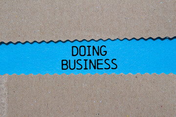 Doing business message written on ripped torn paper on blue background. Conceptual doing business...