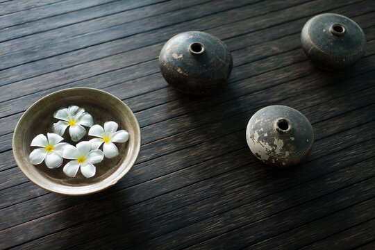 Petals of the orchid flower in a bowl of water. Oil lamps.