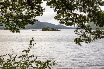 A small island in the middle of a lake framed with trees and foliage, Norfolk Island, Ullswater, The Lake District, Cumbria, England